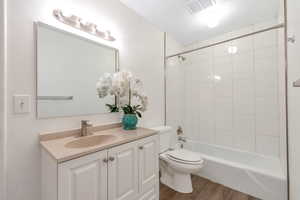 Full bathroom featuring tiled shower / bath, toilet, hardwood / wood-style flooring, and vanity