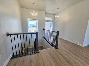 Stairs with a chandelier and hardwood / wood-style flooring