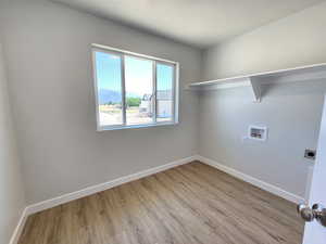 Laundry area featuring hookup for a washing machine, light hardwood / wood-style floors, and electric dryer hookup