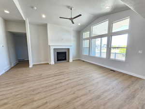 Unfurnished living room with ceiling fan, light hardwood / wood-style flooring, and a tile fireplace