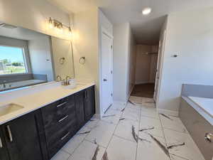 Bathroom featuring tile floors, dual vanity, and a bath to relax in