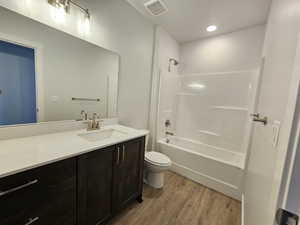 Full bathroom featuring tub / shower combination, vanity, toilet, and hardwood / wood-style floors