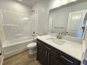 Full bathroom with  shower combination, large vanity, toilet, and wood-type flooring