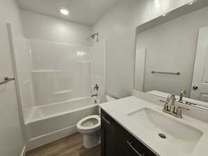 Full bathroom featuring hardwood / wood-style flooring, bathtub / shower combination, vanity, and toilet