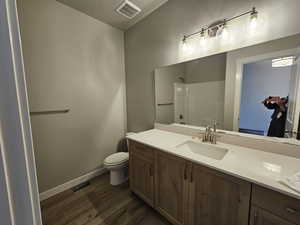 Bathroom featuring hardwood / wood-style flooring, toilet, and vanity