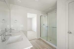 Bathroom featuring hardwood / wood-style floors, a shower with shower door, and dual bowl vanity