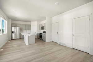 Kitchen with light hardwood / wood-style floors, sink, a center island with sink, and stainless steel appliances