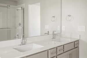 Bathroom featuring an enclosed shower and dual bowl vanity