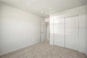 Unfurnished bedroom with light carpet and a closet