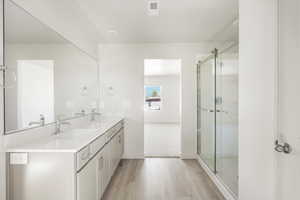 Bathroom featuring a shower with door, hardwood / wood-style flooring, and double vanity