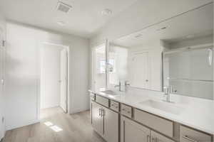 Bathroom with dual vanity, a textured ceiling, and hardwood / wood-style floors