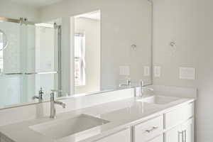 Bathroom with a healthy amount of sunlight, walk in shower, and dual bowl vanity