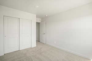 Unfurnished bedroom featuring light carpet and a closet