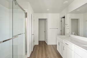 Bathroom featuring double vanity, an enclosed shower, and hardwood / wood-style flooring