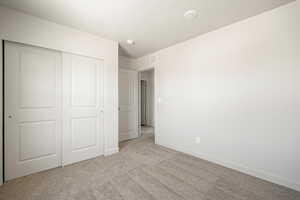 Unfurnished bedroom with light carpet and a closet