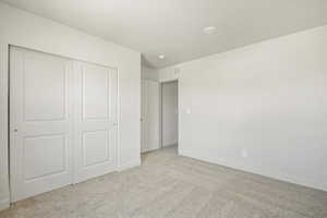 Unfurnished bedroom with a closet and light colored carpet