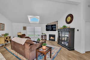 Living room with lofted ceiling with skylight and light wood-type flooring