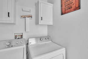 Laundry area with separate washer and dryer and cabinets