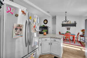 Kitchen featuring a notable chandelier, decorative light fixtures, white cabinetry, stainless steel fridge, and light hardwood / wood-style flooring