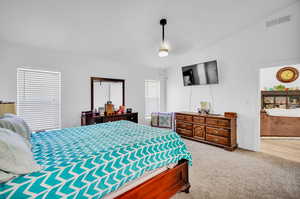 Carpeted bedroom featuring vaulted ceiling and ceiling fan