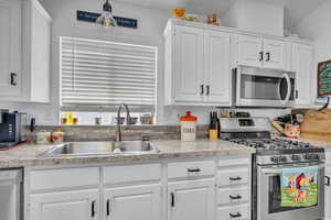 Kitchen with sink, stainless steel appliances, and white cabinets