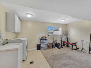 Clothes washing area with washer and dryer, washer hookup, light tile flooring, and cabinets