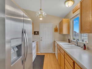 Kitchen featuring lofted ceiling, light hardwood / wood-style flooring, white appliances, pendant lighting, and sink