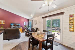 Carpeted dining room featuring ceiling fan and lofted ceiling