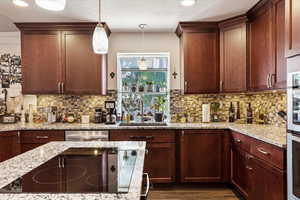 Kitchen with hardwood / wood-style flooring, decorative light fixtures, backsplash, sink, and dishwasher