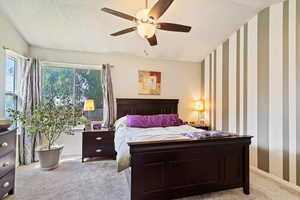 Carpeted bedroom featuring ceiling fan and a textured ceiling