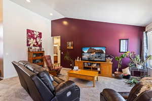 Living room with a textured ceiling, carpet floors, and lofted ceiling