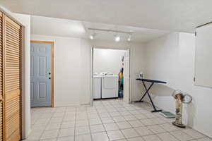 Interior space featuring track lighting, separate washer and dryer, and light tile flooring