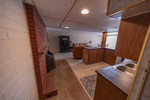 Interior space with brick wall, a paneled ceiling, sink, and light wood-type flooring