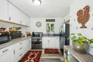 Kitchen featuring white cabinetry, sink, black appliances, and hardwood / wood-style flooring