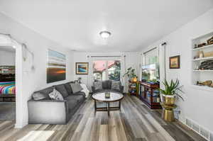 Living room with built in features and wood-type flooring