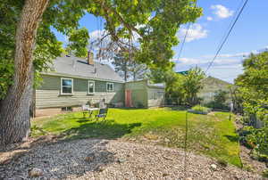 Rear view of property with a lawn with mature trees