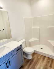 Bathroom featuring a shower, hardwood / wood-style floors, vanity, and toilet