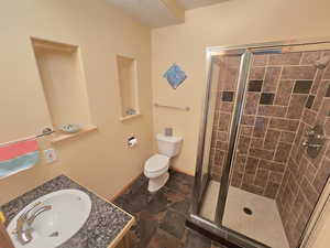 Bathroom with vanity, toilet, tile floors, and a shower with door