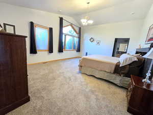 Carpeted bedroom with an inviting chandelier and lofted ceiling