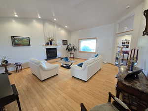 Living room with high vaulted ceiling and light hardwood / wood-style floors