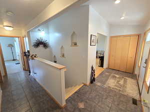 Hallway featuring vaulted ceiling and dark tile floors