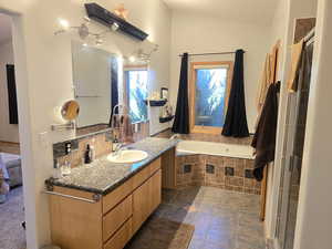 Bathroom featuring a wealth of natural light, tile flooring, tiled bath, and large vanity