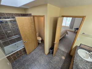 Bathroom featuring tiled shower, a textured ceiling, tile floors, vanity, and toilet