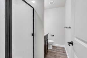 Bathroom with an enclosed shower, hardwood / wood-style flooring, toilet, and vanity