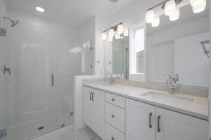 Bathroom featuring dual vanity, an enclosed shower, and tile floors