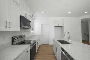 Kitchen featuring stainless steel appliances, light hardwood / wood-style flooring, white cabinets, and sink