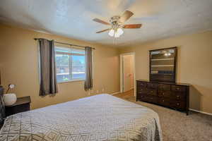 Bedroom featuring a textured ceiling, carpet, and ceiling fan