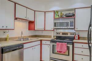 Kitchen with sink, stainless steel appliances, and white cabinetry