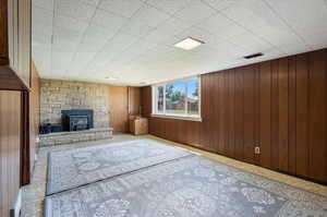 Unfurnished living room with wooden walls, a fireplace, and a wood stove