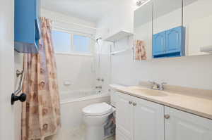 Full bathroom with toilet, shower / bath combo with shower curtain, and vanity